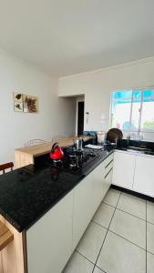 a kitchen with white cabinets and a black counter top at Apto frente pro mar 3 pedra in Itapoa +8 photos