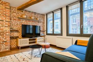 un soggiorno con divano blu e muro di mattoni di Duplex Rue Royale, rooftop, balnéo spa a Lille