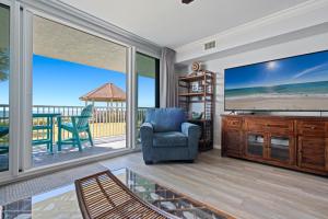 a living room with a large screen tv and a chair at Romar Tower Unit 1A in Orange Beach