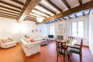Elle comprend un salon doté d'un mobilier blanc et de plafonds en bois. dans l'établissement Large Apartment in the Historic Center of Parma, à Parme