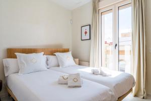 ein Schlafzimmer mit zwei Betten mit weißen Kissen und einem Fenster in der Unterkunft Al Sur Home in Sevilla + 50 Fotos