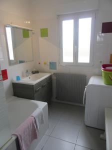 a white bathroom with a sink and a mirror at Maison de vacances avec jardin clos à 300m de la mer in Pouldreuzic +5 photos