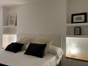 a white bed with black pillows on top of it at Apt Es Poal - Des Puig in Cadaqués