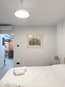 a white bedroom with a bed and a picture on the wall at Cozy Apartment with Acropolis View Rooftop Access in Athens