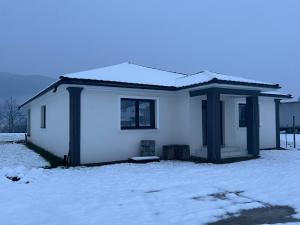 OnceştiVilla Selena的一座白色的小房子,上面有雪