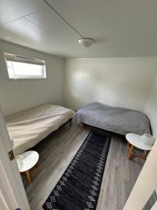 two beds in a small room with a rug at Rolig og avslappende in Tromsø