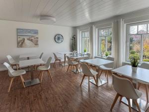 a dining room with tables and chairs and windows at Brise8 - Greetsiel in Krummhörn