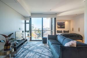 a living room with a blue couch and a bed at 601 The Cosmopolitan in Cape Town