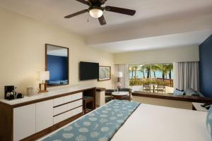 a bedroom with a bed and a desk with a television at Impressive Premium Punta Cana - All Inclusive in Punta Cana