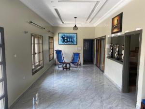 a hallway with two blue chairs in a room at Le Petit Manoir M in Cotonou