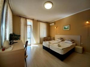 a hotel room with two beds and a desk at Семеен хотел Търнава in Veliko Tŭrnovo