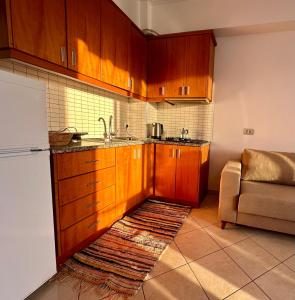 a kitchen with wooden cabinets and a sink and a refrigerator at Fane's Apartments in Himare