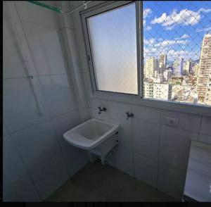 a white sink in a bathroom with a window at AP beira mar in Praia Grande