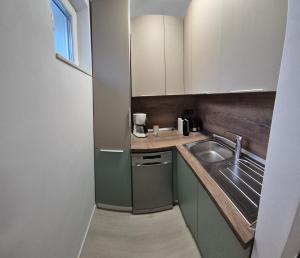 a small kitchen with white cabinets and a sink at Tudor Central Apartment in Bistriţa