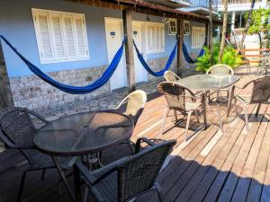 een patio met een tafel, stoelen en hangmatten bij Flat e suítes com cozinha e churrasqueira in Conservatória