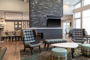 a lobby with a fireplace and chairs and a table at Residence Inn by Marriott Detroit Dearborn in Dearborn