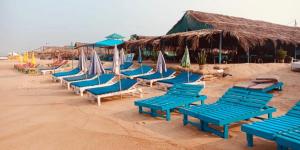 un grupo de sillas y sombrillas azules en una playa en D'Souzas Guest House, en Calangute