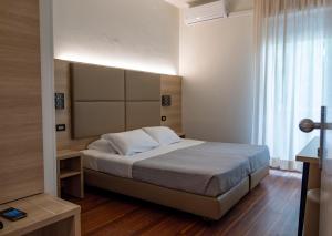 a bedroom with a bed with white sheets and a window at Hotel St Gregory Park in Rimini