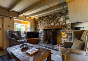 a living room with a stone fireplace and a wooden table at Clydfan - Newport in Newport Pembrokeshire