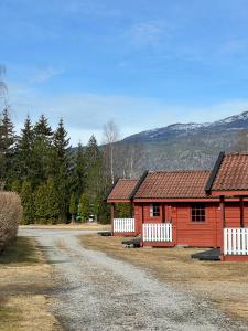een rode schuur met een wit hek naast een onverharde weg bij Sanda Camping og Hytteutleie in Øvrebø
