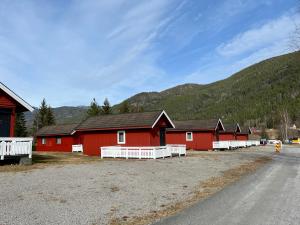 een groep rode schuren met bergen op de achtergrond bij Sanda Camping og Hytteutleie in Øvrebø +33 foto's