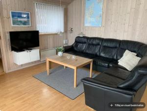 a living room with a black leather couch and a coffee table at 4 bedrooms and a beautiful view in Vinderup