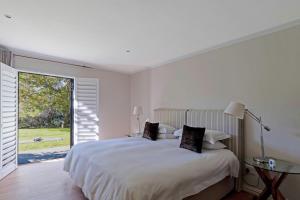 ケープタウンにあるApartment on Constantia wine routeのベッドと大きな窓のある白い寝室 +15枚の写真