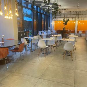 a restaurant with white tables and chairs and windows at THE ONE - Flat Batel Premium in Curitiba