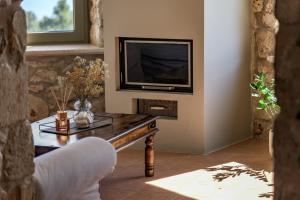 ein Wohnzimmer mit Fernseher und Couchtisch in der Unterkunft GAGOUINOS COTTAGE in Koríthion