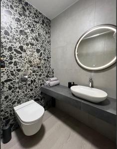 a bathroom with a sink and a toilet and a mirror at Свіжі апартаменти в центрі міста новобудові на Проскурівське підпілля 110а in Khmelnytskyi +20 photos