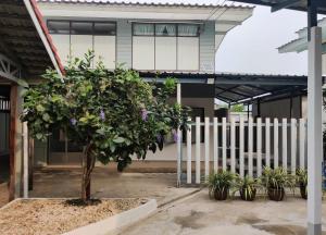 a tree in front of a building with a fence at The Neighbors in Chanthaburi