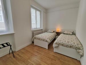 Cette chambre blanche dispose de 2 lits et de 2 fenêtres. dans l'établissement L'hermine, à Saint-Malo