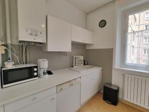 d'une cuisine avec des placards blancs, un four micro-ondes et une fenêtre. dans l'établissement L'hermine, à Saint-Malo