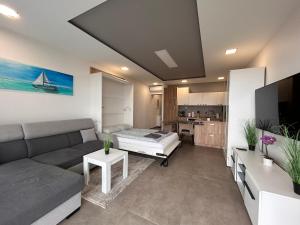 Una sala de estar con un sofá y una cocina. en Fehér Hullám Apartman, en Balatonalmádi