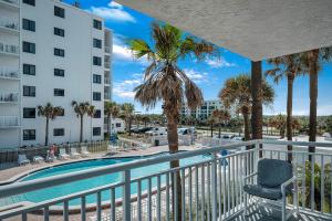 a resort balcony with a pool and palm trees at Take in the oceanfront corner views located on the no-drive beach! in New Smyrna Beach
