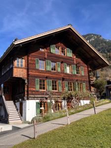 una grande casa in legno con finestre con persiane verdi di Blüemlisalp-Huus im Kiental a Kiental