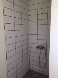 a shower with a hose in a white tiled bathroom at Privat hus mellem Legoland og Givskud Zoo in Gadbjerg