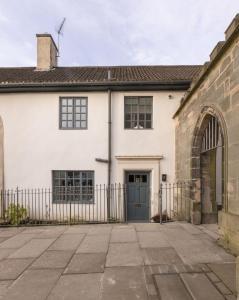 a white house with a blue door and a gate at Bishop Lightfoot Cottage in Bishop Auckland
