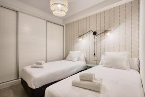 塞维利亚San Francisco Top-Luxury, by Homing U的配有白色墙壁的小客房内的两张床