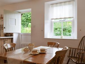 a kitchen with a wooden table with chairs and a window at Roundhill Cottages 1 in Grasmere