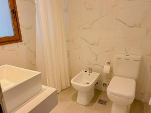 a white bathroom with a toilet and a sink at Jade Residencias de Mar in Villa Gesell +15 photos