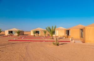 a group of tents in a desert with a red hose at Kalimba Luxury Desert Camp in Merzouga