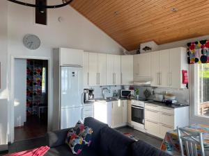a kitchen with white cabinets and a couch at Rantahelmi-huvila in Eurajoki +18 photos