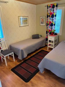 a bedroom with two beds and a chair and a window at Rantahelmi-huvila in Eurajoki