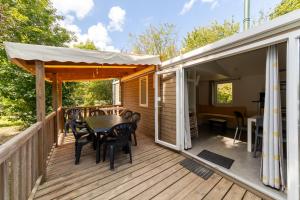 a wooden deck with a table and chairs on it at Camping Paradis Vallée du Lot in Pujols