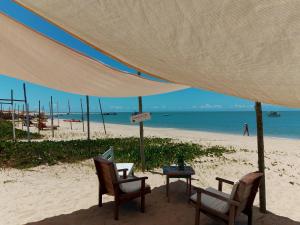 a table and chairs on a beach under a tent at Pousada da Vila restaurante in Corumbau