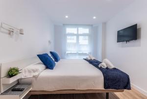 ビルバオにあるAzkuna Home Apartmentの白いベッドルーム(青い枕の大型ベッド付) +19枚の写真