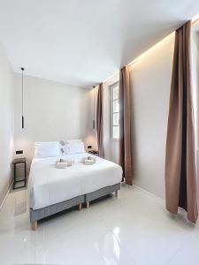 a white bedroom with a large bed with white sheets at Luxury Apartment - Central Cannes, near Beach & Palais - LRACANNES in Cannes