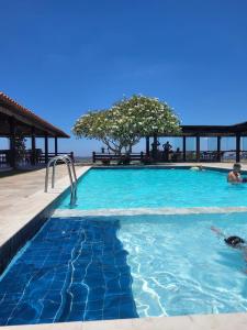 una piscina con acqua blu e alberi sullo sfondo di Monte Castelo Gravatá - Flat Aconchegante a Gravatá