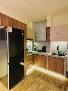 a kitchen with a black refrigerator and wooden cabinets at Moderno Departamento en Estreno in Arequipa